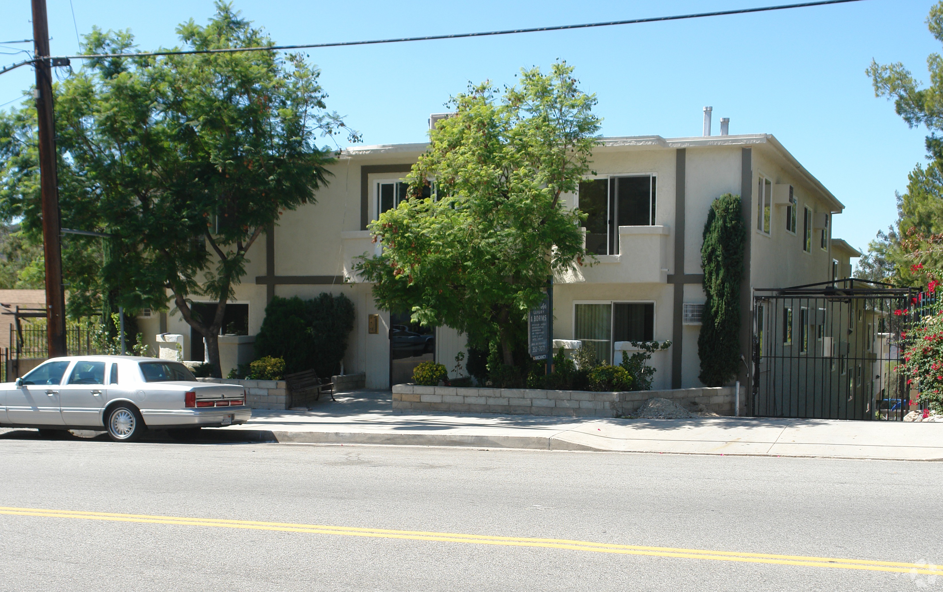 A white car is parked on the side of the street in front of a house.